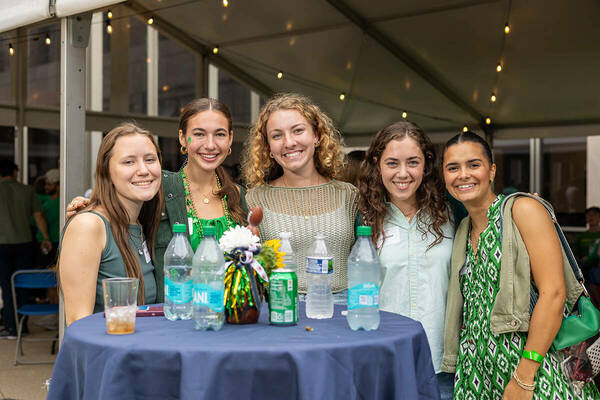 group of 5 female students standing around table and posing for picture