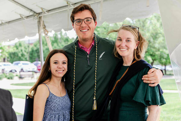 Will Grannis is a Caucasian man with brown hair and glasses. He is posing with a blonde Caucasian woman and a brunette Caucasian woman.