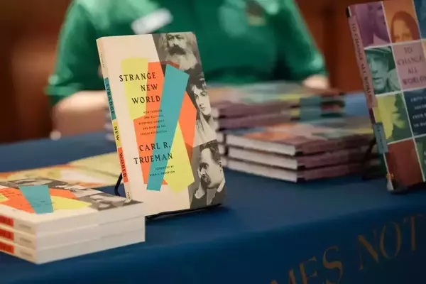 Carl Trueman's 'Strange New World' (colorful cover with portraits) and 'To Change All Worlds' on a blue Notre Dame table.